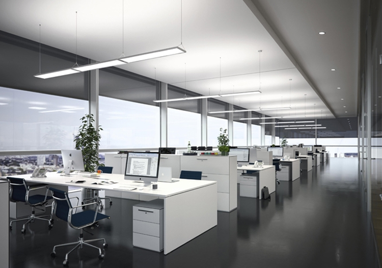 The image showcases a sleek and modern office space characterized by large windows that let in an abundance of natural light, complemented by overhead lighting. The office layout features rows of white desks, each equipped with computer monitors and ergonomic office chairs, creating an organized and efficient workspace.