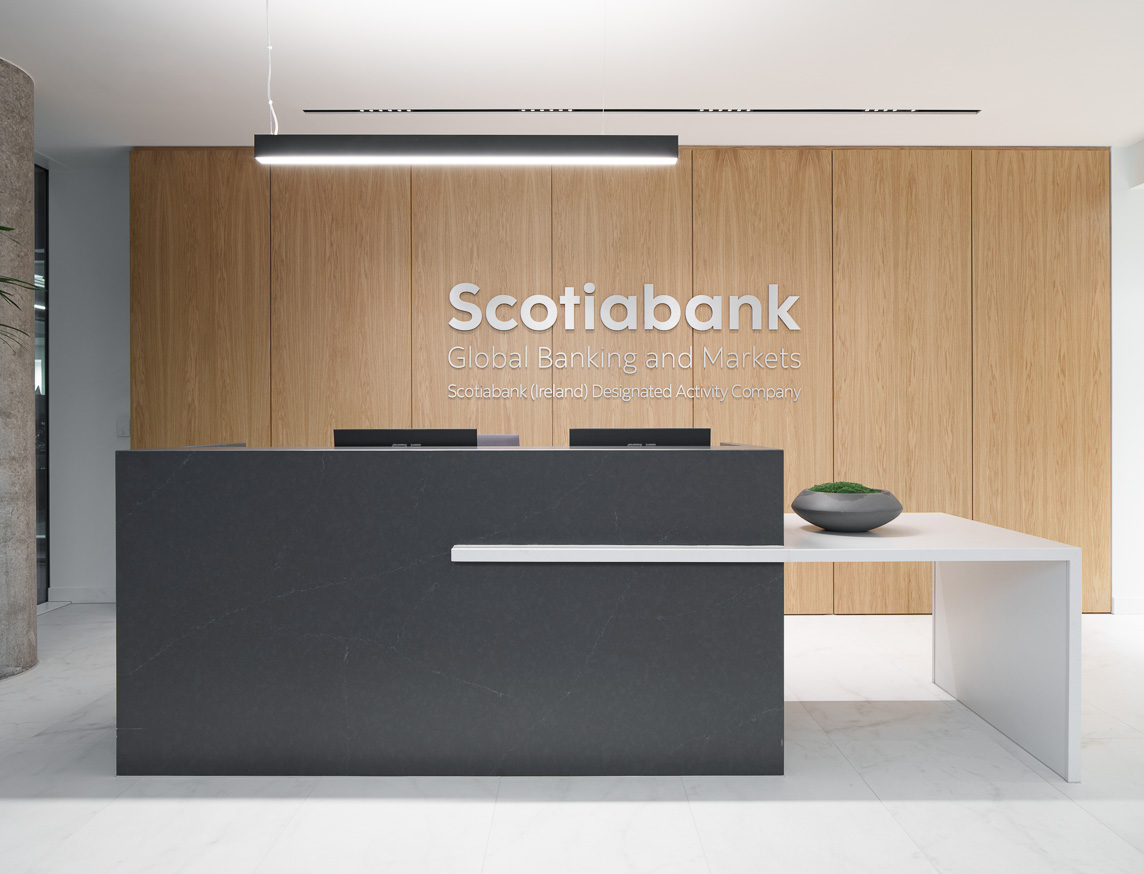 Scotiabank Global Banking and Markets reception area with wooden panel wall, logo, dark grey desk, and linear suspension lights for a modern, professional look